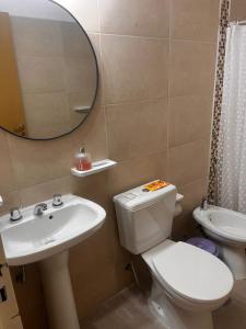 a bathroom with a toilet and a sink and a mirror at Lihuel AG in Alta Gracia +19 photos