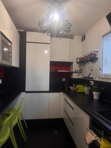 a kitchen with white cabinets and a chandelier at La Maison du Routard in Évreux