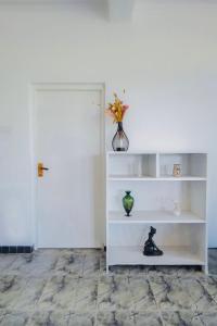 a white book shelf with a vase on it at Cloud Nest Hanthana in Kandy