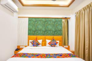 a bedroom with a large bed with colorful pillows at FabHotel Lotus Blue in Bhopal