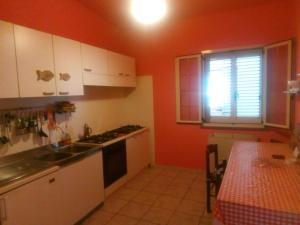 a kitchen with orange walls and white cabinets and a counter at Camera doppia in affitto con bagno privato Interno in Marina di Montenero