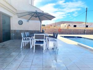 a table and chairs with an umbrella next to a pool at ENJOY House with Large Pool & Jacuzzi in Los Estancos