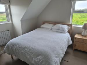 a white bed in a bedroom with two windows at Clochan na Mara - Liscannor, County Clare & Wild Atlantic Way in Liscannor