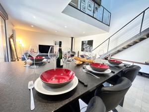 einen Esstisch mit roten Tellern und Weingläsern in der Unterkunft Calme et détente avec jacuzzi, jardin et terrasse in Trigny