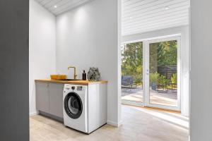 a washer and dryer in a kitchen with a patio at Arkitekttegnet Sommerhus Tæt På Vandet in Marielyst