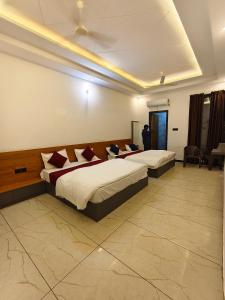 una stanza d'albergo con due letti e un uomo in piedi nella stanza di Hotel CM Palace Khatu Shyam a Khātu