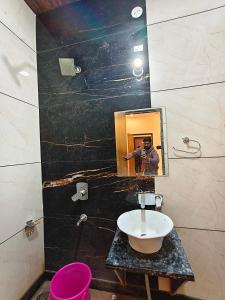 un uomo che scatta una foto di un bagno con lavandino di Hotel CM Palace Khatu Shyam a Khātu