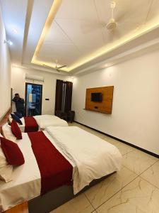 una camera da letto con due letti e una TV a parete di Hotel CM Palace Khatu Shyam a Khātu Altre 14 foto