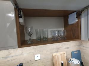 eine Reihe von Weingläsern auf einem Regal in der Unterkunft Elegant Apartments FREE PARKING in Leszno + 46 Fotos