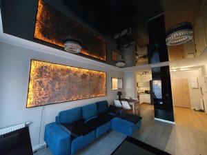ein Wohnzimmer mit einem blauen Sofa und Gemälden an der Wand in der Unterkunft Elegant Apartments FREE PARKING in Leszno