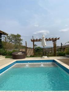 a swimming pool with an umbrella and an umbrella at Casa Penedo Vista da Serra in Itatiaia