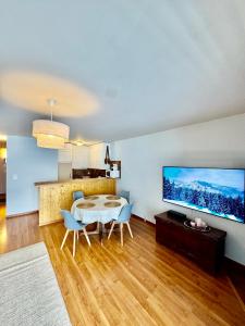 ein Wohnzimmer mit Tisch und Stühlen und einem Fernseher in der Unterkunft magnifique appartement au centre de Montana in Crans-Montana + 3 Fotos