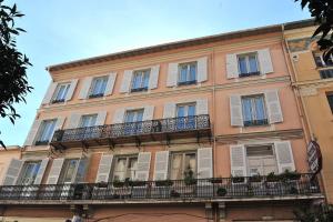 a large pink building with windows and balconies at Hotel Louvia in Menton