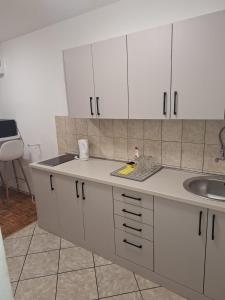 a kitchen with white cabinets and a sink at San centar apartment in Banja Luka