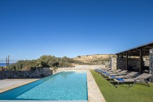 a villa with a swimming pool and lounge chairs at Villa Theano in Triopetra +70 photos