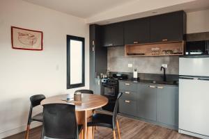 Colonia ChapadmalalDread Shack Nodo Norte 1 - Casa en Complejo Zona Santa Isabel, Chapa Para 4 PAX Con Parrilla - Hola Sur的厨房配有黑色橱柜、桌子和冰箱。