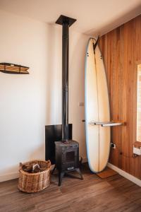 Colonia ChapadmalalDread Shack Nodo Norte 1 - Casa en Complejo Zona Santa Isabel, Chapa Para 4 PAX Con Parrilla - Hola Sur的房间里有一块冲浪板和一个柴火炉