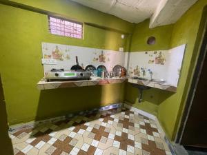 a kitchen with green walls and a tiled floor at Munsiyari Eco homestay in Munsyari