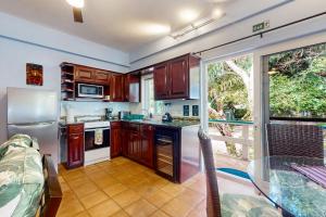 une cuisine avec des placards en bois et une grande fenêtre dans l'établissement Condo #24 @ Beachside Villas, à Placencia