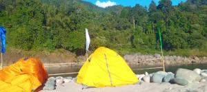 two tents sitting on the shore of a river at Sunset Riverside Camping in Dawki