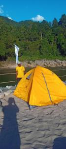 a man standing next to a large yellow tent at Sunset Riverside Camping in Dawki