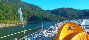 an orange tent next to a body of water at Sunset Riverside Camping in Dawki