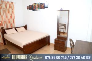 een slaapkamer met een bed, een spiegel en een tafel bij Aluvihare Residence in Matale