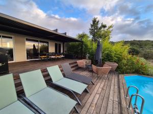 a deck with chairs and a swimming pool next to a house at La tête sous les étoiles in Lézignan-la-Cèbe