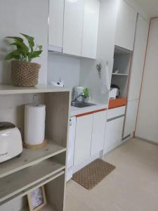 アンサンにあるHigh City view Room with Netflixの小さなキッチン(白いキャビネット、鉢植えの植物付)