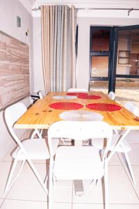 Un comedor con una mesa de madera y sillas blancas. en @Home BnB, en Maseru