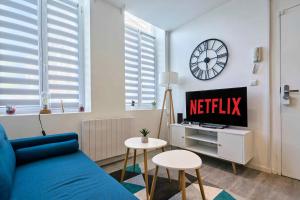 ein Wohnzimmer mit einem blauen Sofa und einer Uhr in der Unterkunft Le Duo - Les Demeures d'Adrien in Carvin