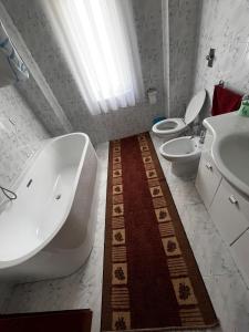 un bagno con due WC, una vasca e un lavandino di La Mary a Borşa