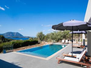 a swimming pool with an umbrella and two lounge chairs and an umbrella at Tina by Vintage Travel in Spartokhórion