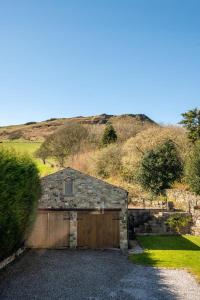 Ein Steingebäude mit Garage, im Hintergrund ein Hügel in der Unterkunft Churn Barn in Chinley