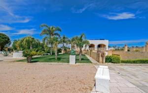 una residencia con palmeras y un edificio en Le Lantane - Luxury Rooms, en Alessano