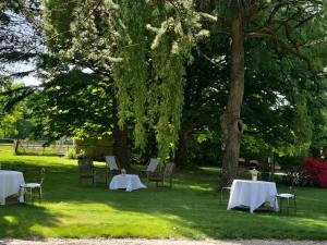 a group of tables and chairs under a tree at Chambres à la campagne La Tuilerie in Prêtreville