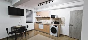 a kitchen with a washer and dryer and a table at Apartament Atlas in Popeşti-Leordeni
