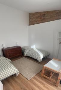 two beds in a room with a table and a rug at Le Léon in Saint-Léon
