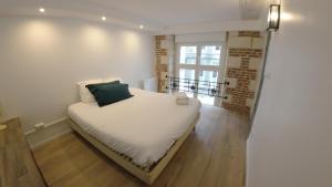 a white bed in a room with a window at Loft industriel - hyper centre cambrai in Cambrai
