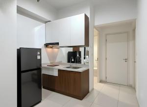 Una cocina con un refrigerador negro y un fregadero. en Apartemen Anderson 03 Pakuwon mall Luxury Studio Apartment Connecting Mall, Pool & City View, en Surabaya