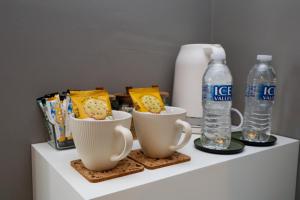 a shelf with two cups and a bottle of water at The Albany Rooms Bexhill in Bexhill
