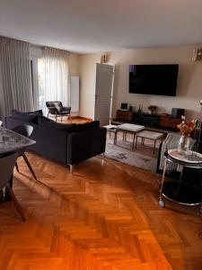 a living room with a black couch and wooden floors at 3 bedrooms with Tour Eiffel view in Issy-les-Moulineaux