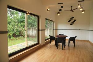 Bekal Eden Resort في Kotikulam: غرفة طعام مع كراسي وطاولة ونوافذ