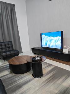 Una sala de estar con televisión y una mesa de café. en Cozy Haven 暖心居, en Simpang Ampat