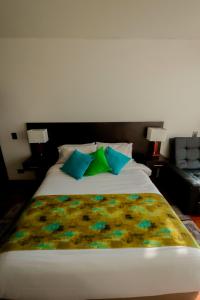 a bed with blue and green pillows on it at Hotel Laverdieri 