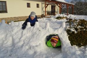 zwei Kinder spielen in einem Loch im Schnee in der Unterkunft Penzion pod Čeřinkem in Mirošov