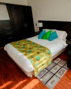 a bedroom with a large white bed with blue and green pillows at Hotel Laverdieri 