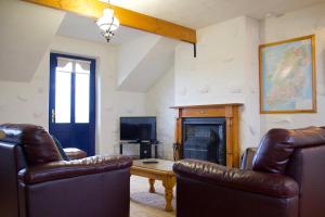 ein Wohnzimmer mit 2 Ledersesseln und einem Kamin in der Unterkunft Atlantic View Cottages in Doolin