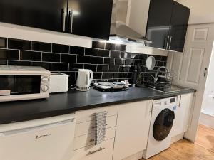 une cuisine avec un micro-ondes et un lave-linge dans l'établissement Preston Room Let, à Yeovil