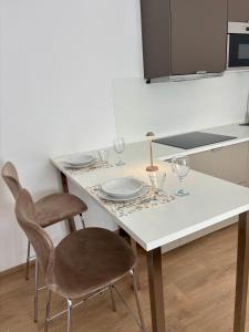 una cucina con tavolo bianco, sedie e bicchieri di Chorus Home a Bergamo